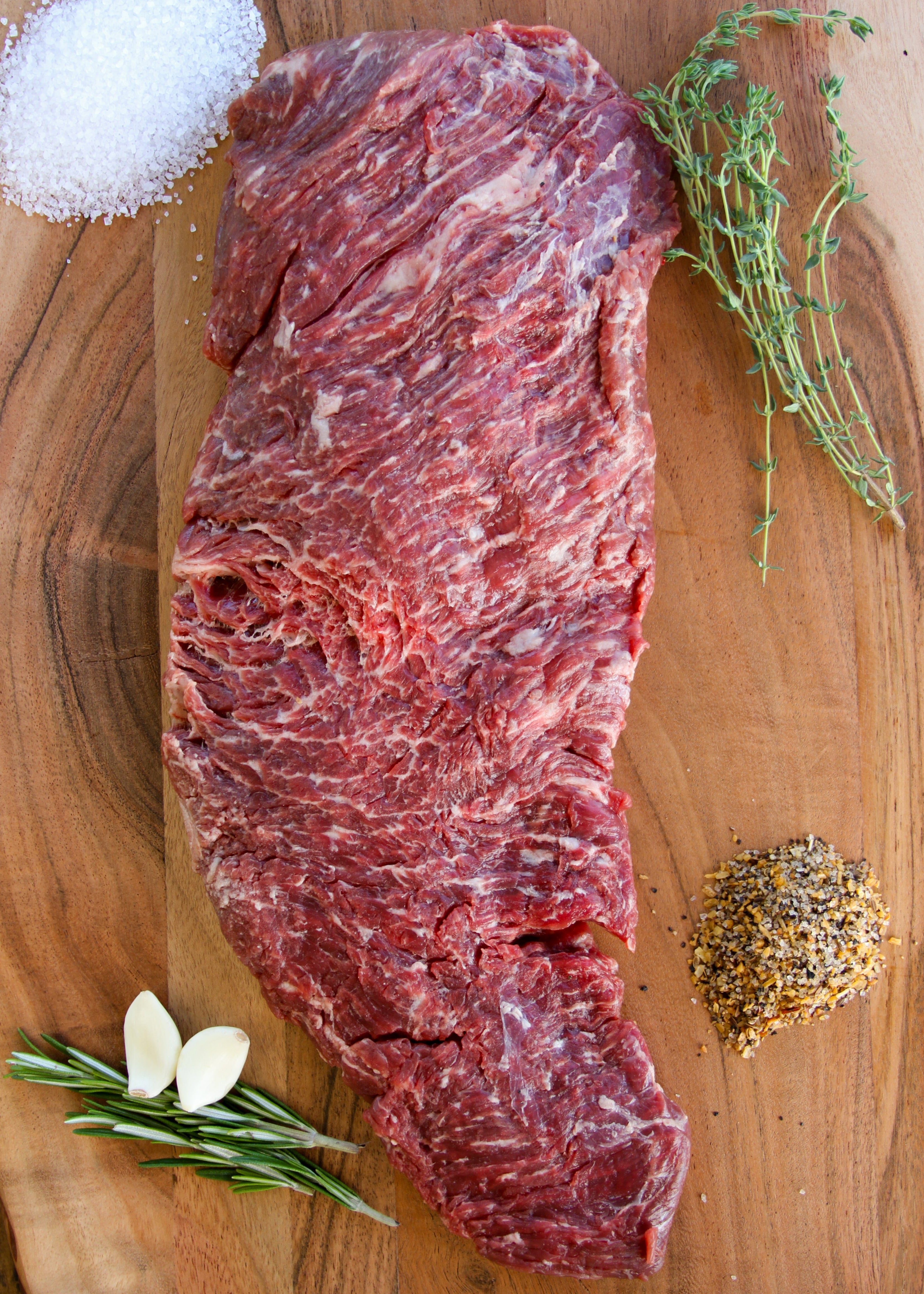 Wagyu steak on a wooden cutting board with herbs and salt