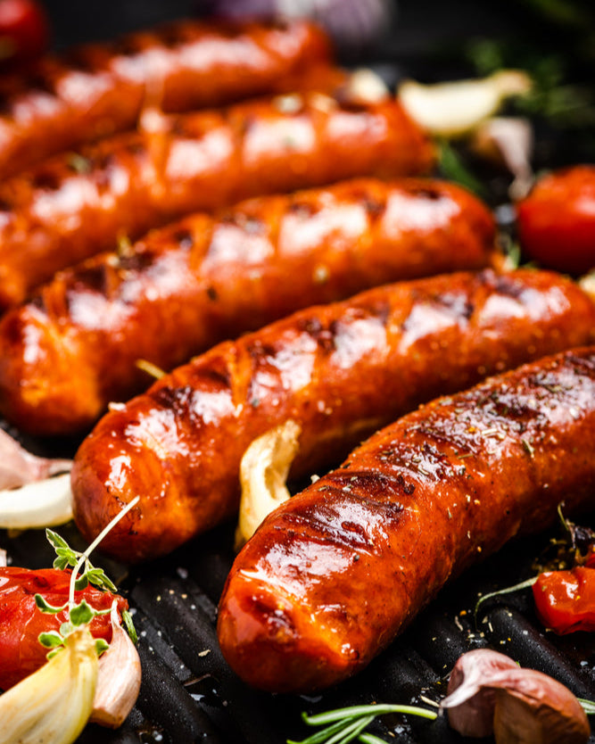 Grilled pork sausages on a grill with vegetables