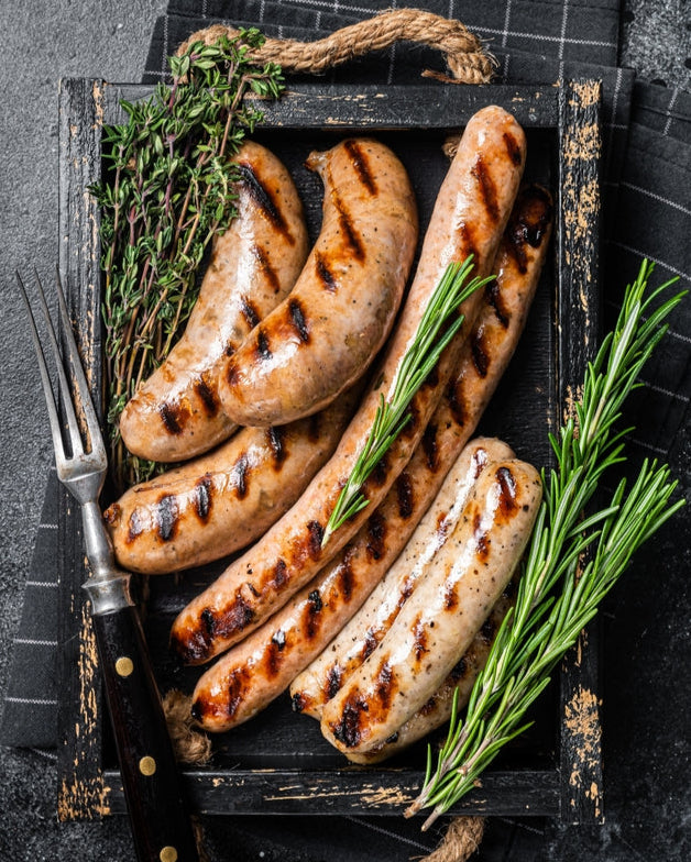 Grilled sausages with herbs on a dark surface