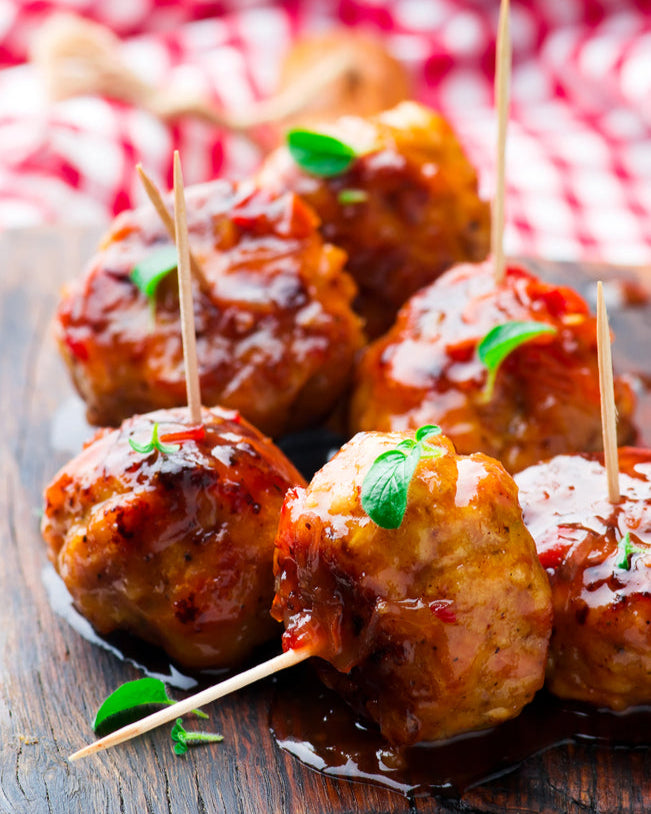 Wooden board with skewered pork meatballs on a checkered cloth background